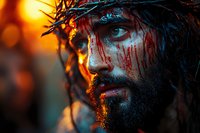 Dramatic portrait of bearded man with crown of thorns and blood makeup against fiery orange background, artistic religious interpretation with cinematic lighting.