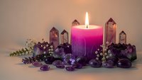 Spiritual meditation setup with burning pink candle surrounded by amethyst crystals and healing stones for wellness rituals and mindfulness practice.
