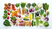 Fresh organic vegetables arranged in colorful rows on white background including tomatoes carrots broccoli peppers eggplant cauliflower leafy greens.