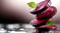 Fresh beetroot slices stacked with green leaves on reflective surface. Organic purple vegetable for healthy cooking, nutrition concepts and culinary designs.