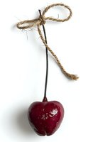 Red decorative apple ornament with natural twine bow tied on stem against white background, isolated object for holiday and seasonal decor styling.