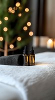 Massage oil bottles on white towel with soft bokeh lights and Christmas tree in background creating relaxing spa atmosphere for wellness and aromatherapy treatments.