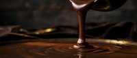 Melted chocolate dripping from spoon onto dark surface creating ripples and swirls, ideal for food and beverage marketing.