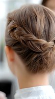 Elegant French braid wrapped into a low bun hairstyle shown from behind on light brown hair, demonstrating intricate braiding technique for special occasions.