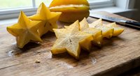 Fresh star fruit carambola sliced on wooden cutting board showing natural star shape cross sections ready for healthy snacking or tropical recipe preparation.