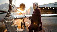 Professional blonde businesswoman boarding private jet at sunset airport with luxury travel lifestyle and corporate aviation background.