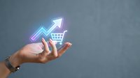 Female hand holding glowing virtual shopping cart with upward arrow, symbolizing e-commerce growth, retail sales increase, and online business success.