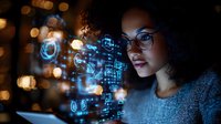 Young African American woman with glasses looking at glowing digital interface with icons and data visualization in dark room with bokeh lights background.