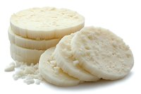 Fresh white cheese rounds sliced and stacked showing creamy texture and crumbly pieces on white background isolated for culinary design projects.