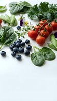 Fresh organic vegetables and fruits on white background with spinach leaves, cherry tomatoes, blueberries, kale and herbs for healthy cooking and nutrition.