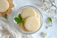 Vanilla macarons with mint garnish in glass bowl on white background with spring blossom decoration, fresh and elegant dessert styling for patisserie menu.