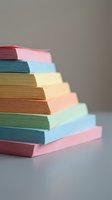 Stack of colorful paper sheets in pastel tones arranged diagonally, showcasing red, pink, blue, yellow, green, and cream colors for design, printing, and creative projects.