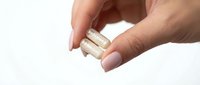 Hand holding white capsule pills on clean background for healthcare and pharmaceutical supplement concepts.