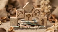 Wooden blocks with environmental icons, recycled paper, and natural materials arranged on burlap for sustainability and eco-friendly design concepts.