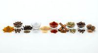 Colorful spices and seasonings arranged in row on white background for culinary cooking and food preparation projects.