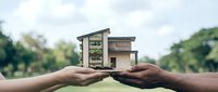 Hands holding miniature modern house model outdoors representing real estate investment, property ownership, home buying dreams and architectural planning concepts.