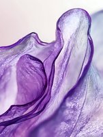 Purple liquid gel texture with flowing waves and bubbles creating abstract cosmetic skincare background for beauty product design and advertising campaigns.