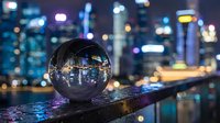 Crystal sphere reflecting illuminated cityscape at night with bokeh lights and urban skyline, suitable for business, technology, and futuristic design projects.