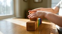 Protective hands covering wooden blocks with colorful stripes on table, symbolizing insurance, safety, security and risk management in business environment.