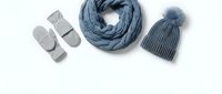 Cozy winter accessories flat lay with knitted scarf, beanie hat and warm slippers in blue and gray tones on white background for seasonal fashion styling.