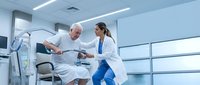 Female doctor assisting elderly male patient with physical therapy exercise equipment in modern medical rehabilitation center.