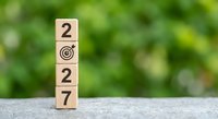 Wooden blocks displaying 2027 with target symbol representing new year goals and business objectives on natural green background.