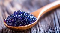 Fresh black caviar on wooden spoon, luxury gourmet food close-up on rustic wooden background. Premium seafood delicacy for fine dining and gastronomy.