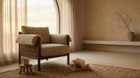 Warm-toned modern living room with mid-century armchair, natural light from sheer curtains, minimalist decor, and neutral earth tones for interior design projects.