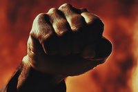 Strong African American fist raised against dramatic red and orange background symbolizing power, unity, resistance and social justice movement.