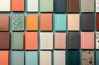 Colorful collection of hardcover notebooks and journals arranged in grid pattern featuring mint, coral, pink and teal colors with some floral patterns and textured covers.