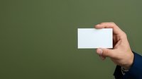 Hand holding blank white business card against green background, suitable for branding, corporate identity, and marketing mockup designs.