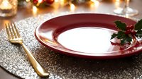 Elegant holiday table setting with burgundy plate, gold fork, and festive decorations on sparkly surface. Perfect for seasonal dining and celebration designs.