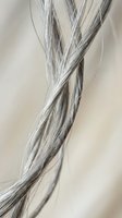 Close-up macro of twisted silver gray hair strands showing detailed texture and natural shine against soft neutral background for beauty concepts.
