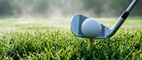 Golf club and ball on green grass ready for shot with blurred background creating professional sports atmosphere for athletic marketing materials.