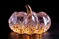 Illuminated glass pumpkin decoration with glowing amber base and crystal clear top, featuring delicate internal bubbles on black background, seasonal autumn decor.