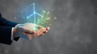 Businessman hands holding glowing wind turbine and green leaves hologram representing renewable energy and environmental sustainability concepts.