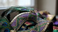 Ornate carnival mask with intricate beadwork and colorful peacock feathers for masquerade ball celebration and festive party decoration.