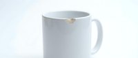 White ceramic mug with small gold leaf detail on rim, blank template for beverage branding, coffee cup mockup for design projects.
