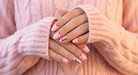 Female hands with pink nail art manicure in cozy knit sweater sleeves. Soft pastel aesthetic for beauty and fashion concepts.