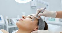 Professional dermatologist performing facial treatment on young woman in modern medical clinic with specialized equipment for skin care procedures.