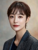 Professional Asian businesswoman with short brown hair and elegant makeup wearing gray blazer for corporate headshot and business portrait photography.