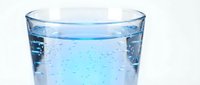 Glass of fresh blue water with bubbles isolated on white background, suitable for beverage, health and wellness design projects.