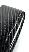 Black carbon fiber material with glossy finish and distinctive weave pattern texture for automotive and industrial design applications.