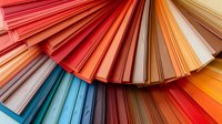 Vibrant color swatch fan displaying spectrum of paint samples arranged in gradient pattern from red through blue to orange tones, close-up view for interior design.