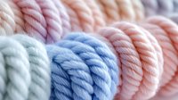 Colorful cotton rope coils in soft pastel shades of pink, blue and mint green arranged in neat rows for crafting and macrame projects.