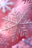 Glittering silver snowflake ornaments on pink background with soft bokeh lights create magical winter holiday atmosphere, macro close-up view.