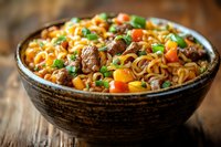 Asian noodles with beef chunks, carrots, green peas and corn in rustic ceramic bowl on wooden table, close up view of traditional stir fry meal.