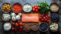Raw salmon fillet with fresh organic ingredients including berries, tomatoes, mushrooms, herbs and grains arranged on dark rustic background for healthy cooking.