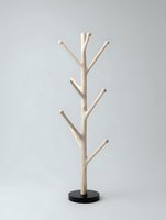 Minimalist wooden coat rack with natural branches on black base against neutral background for modern home organization and storage solutions.