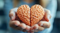 Female hands gently holding anatomical brain model shaped like heart, symbolizing emotional intelligence, mental health awareness and psychology concepts in healthcare.